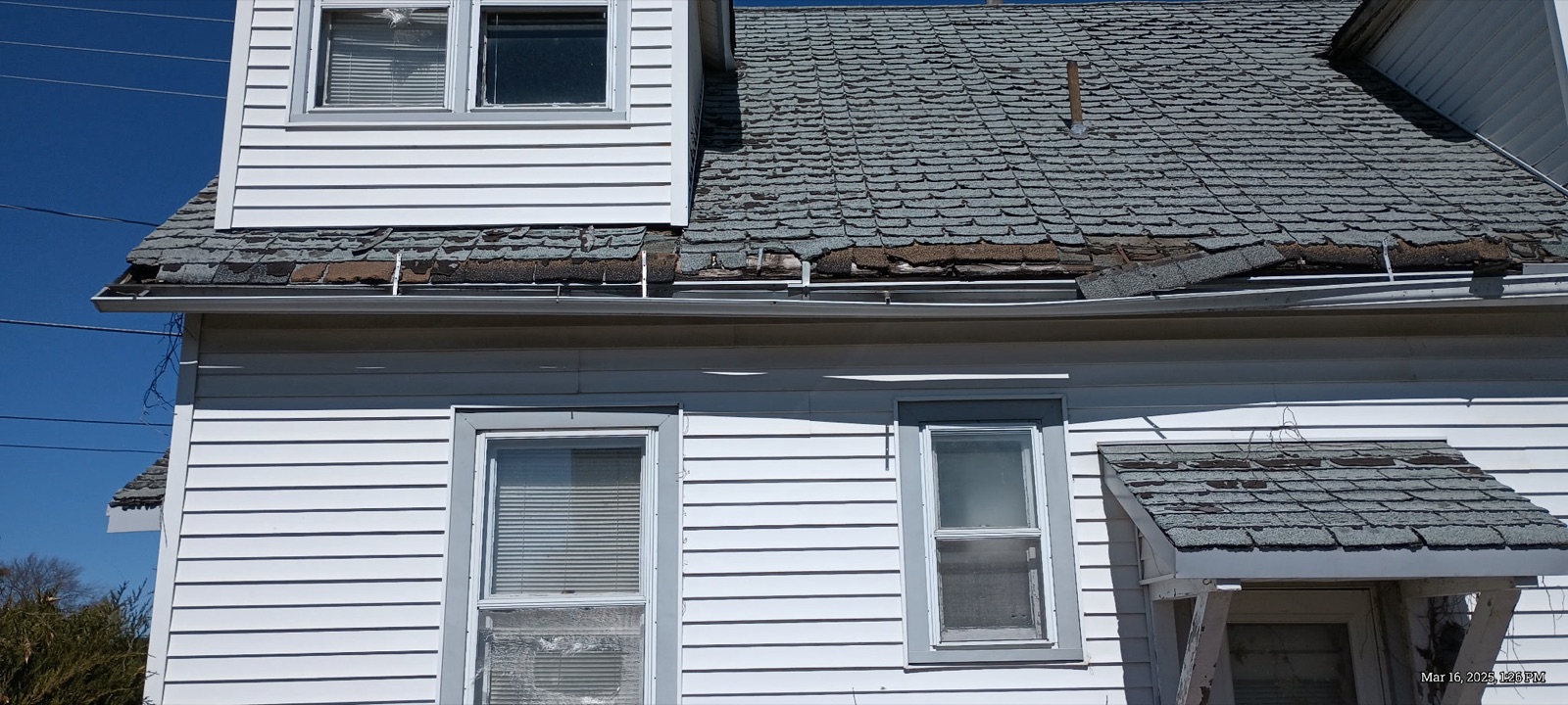 Close-up of hail damage on asphalt roof shingles showing granule loss and dark bruise spots on a Central Iowa home